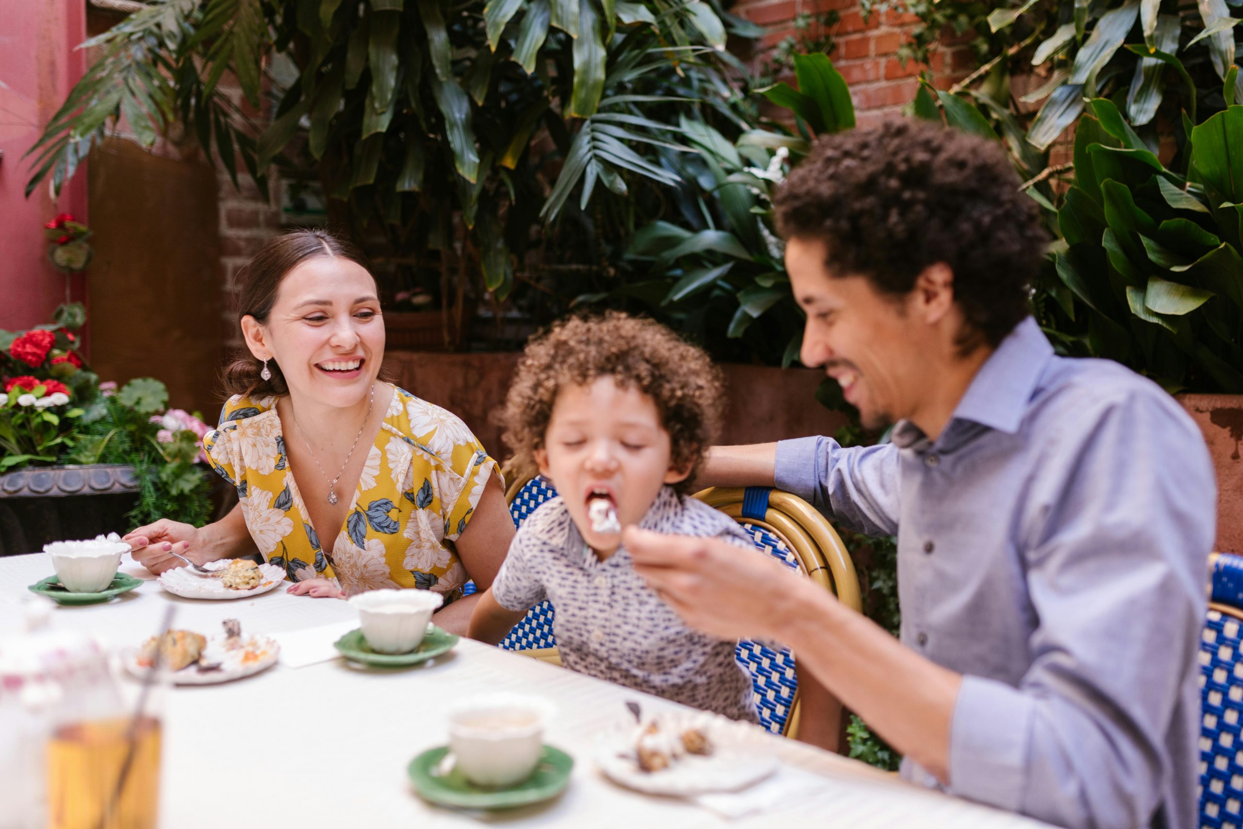 father feeding his son while sitting together at a restaurant table