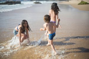 mother and two kids splashing water together at the shoreline