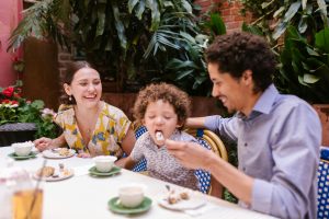 father feeding his son while sitting together at a restaurant table